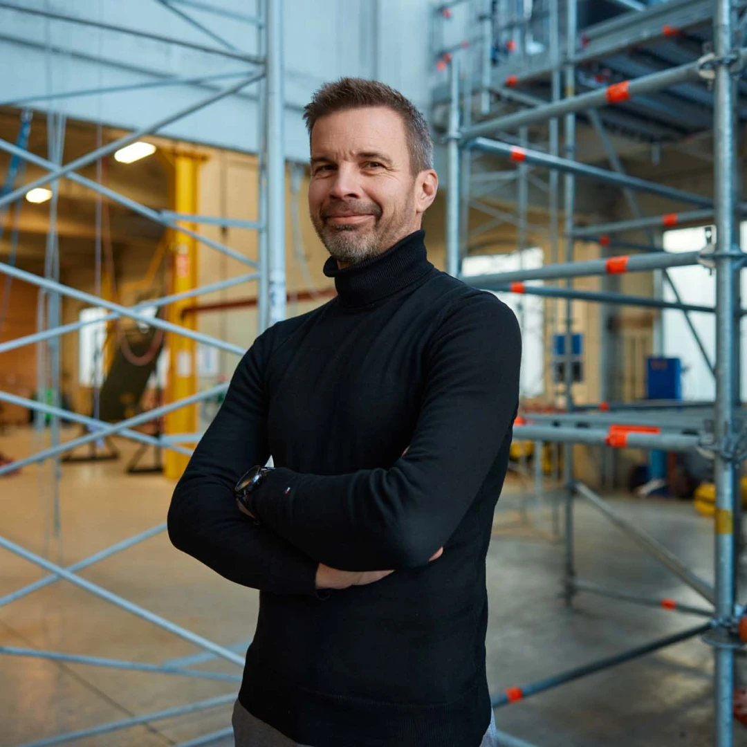 blije man met armen over elkaar poserend in loods