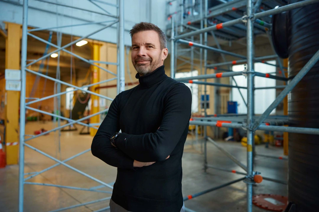 blije man met armen over elkaar poserend in loods