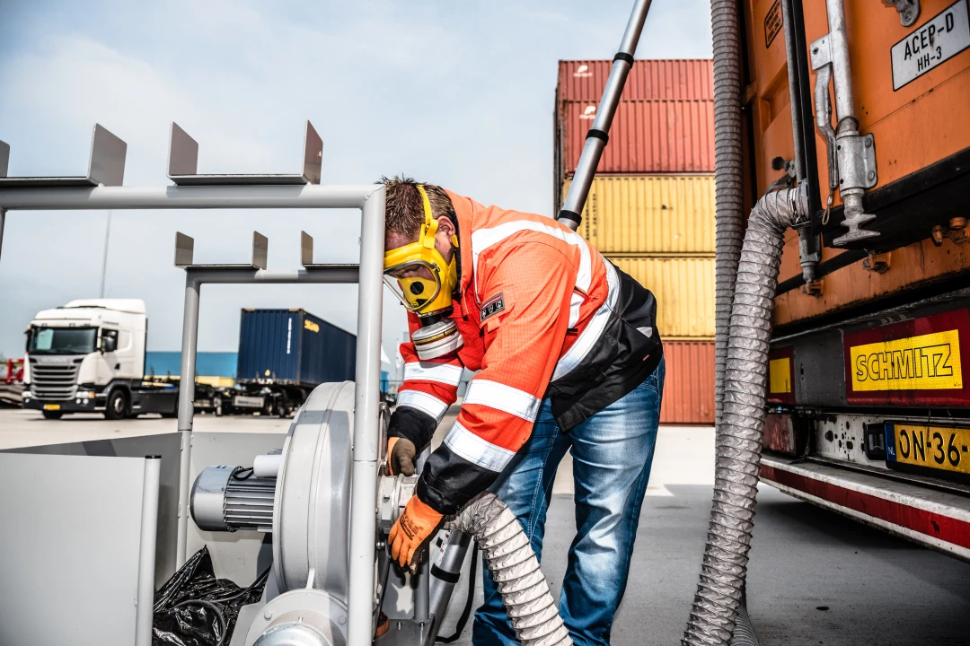 persoon met gasmasker bezig met een slang