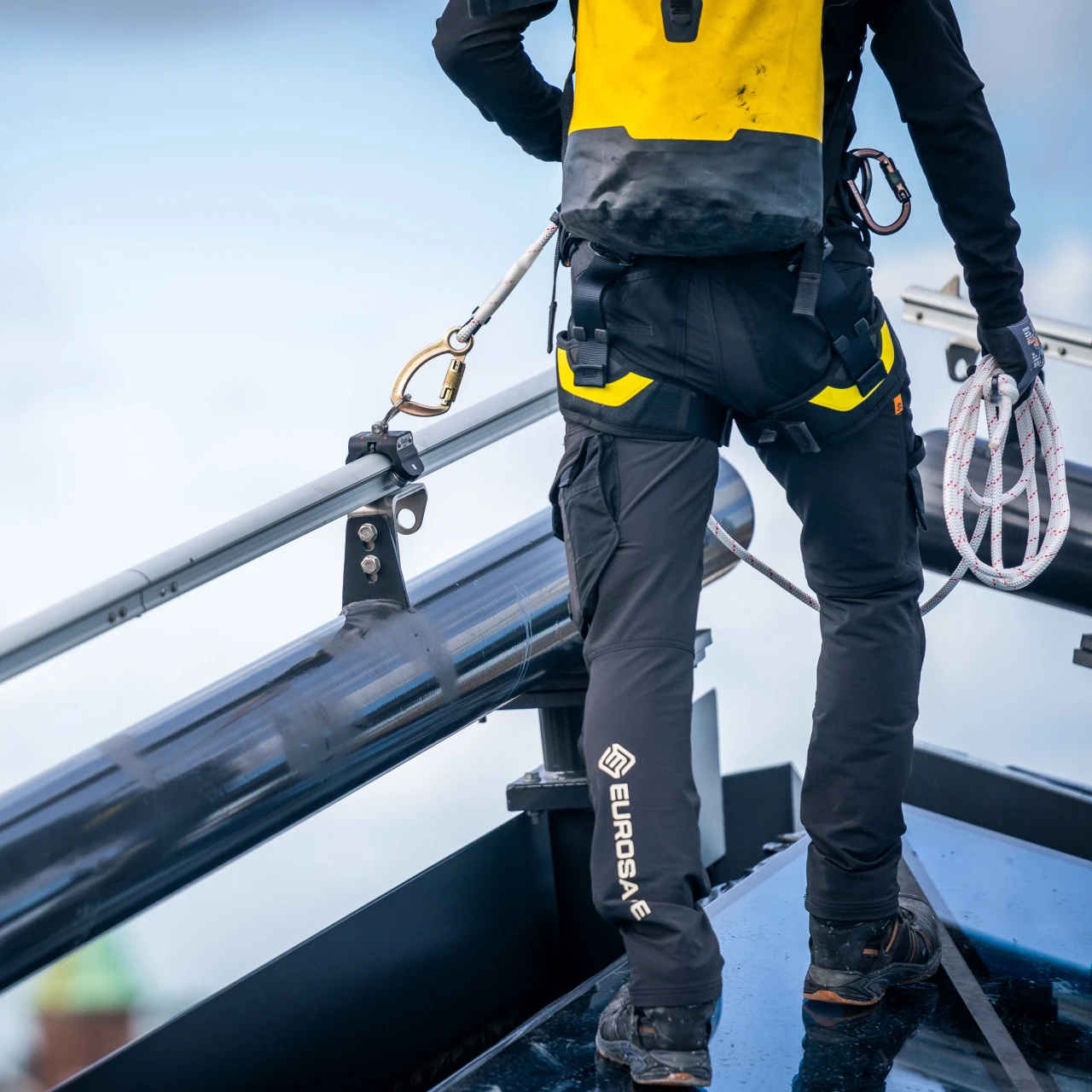 man op dak aan veiligheidslijn met haak en touw