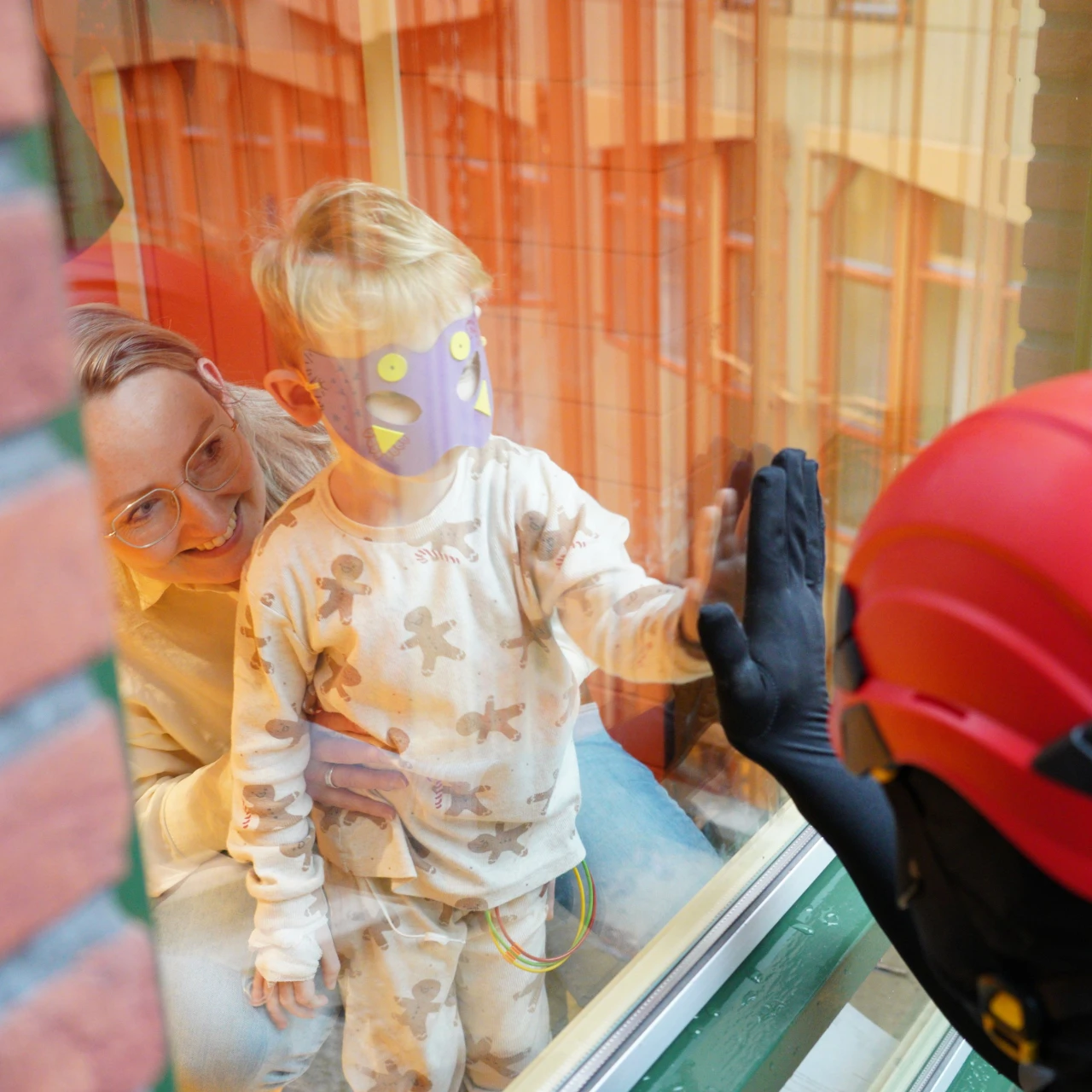 blije moeder met kind die bij het raam contact hebben met een man met helm