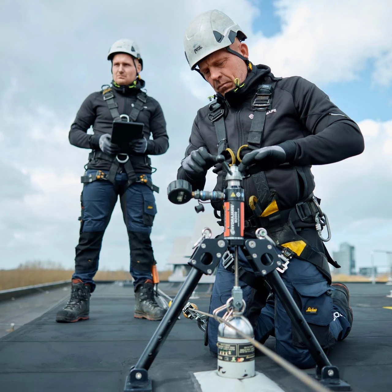 mannen op dak met apparatuur en helm op en harnas aan