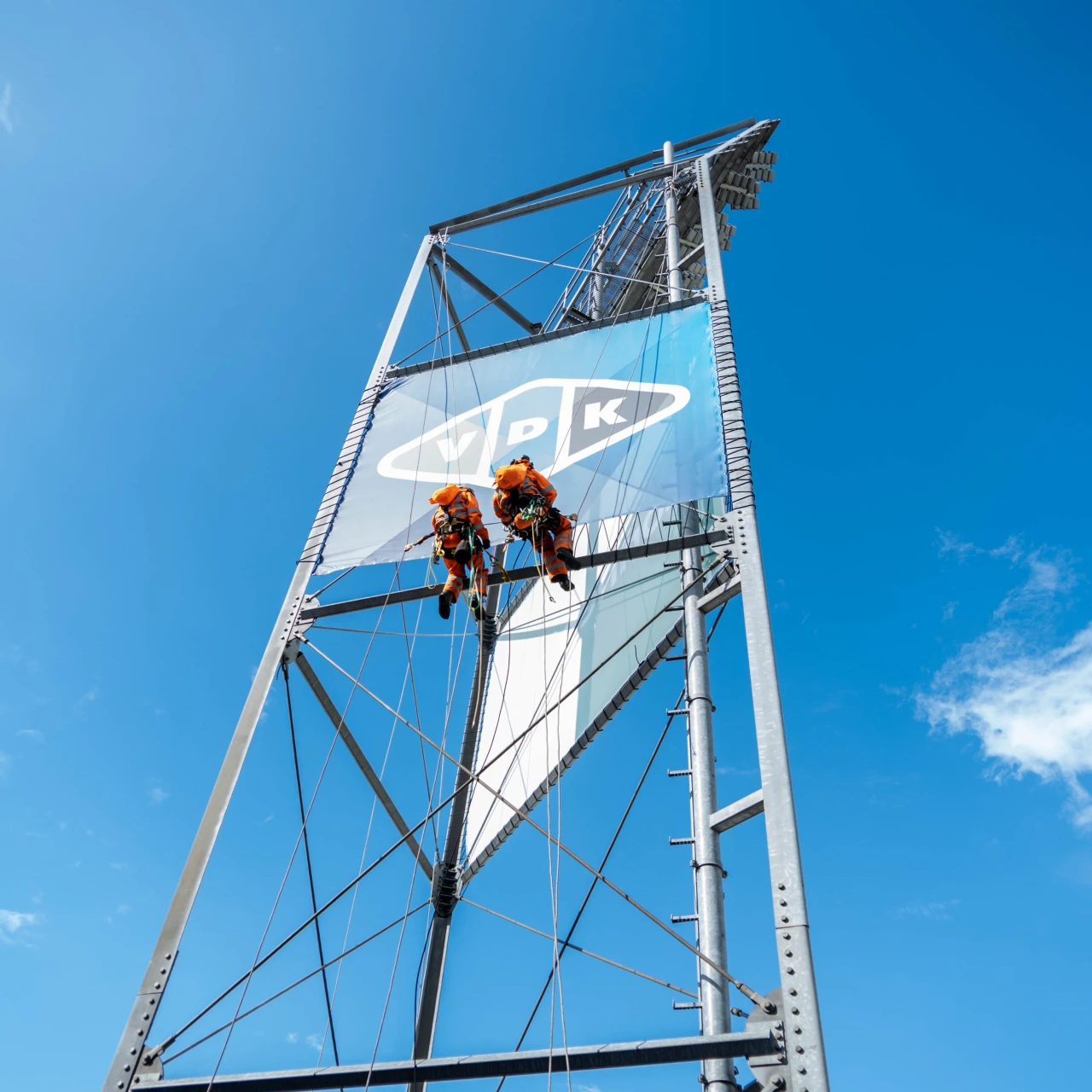 2 mannen die hangen aan een mast van een voetbalstadion