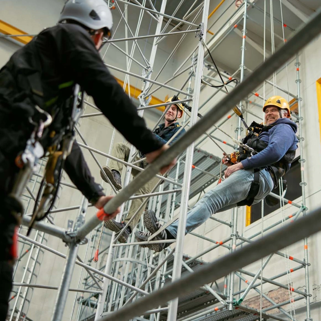personen op hoogte hangend aan touw met helm op en harnas aan