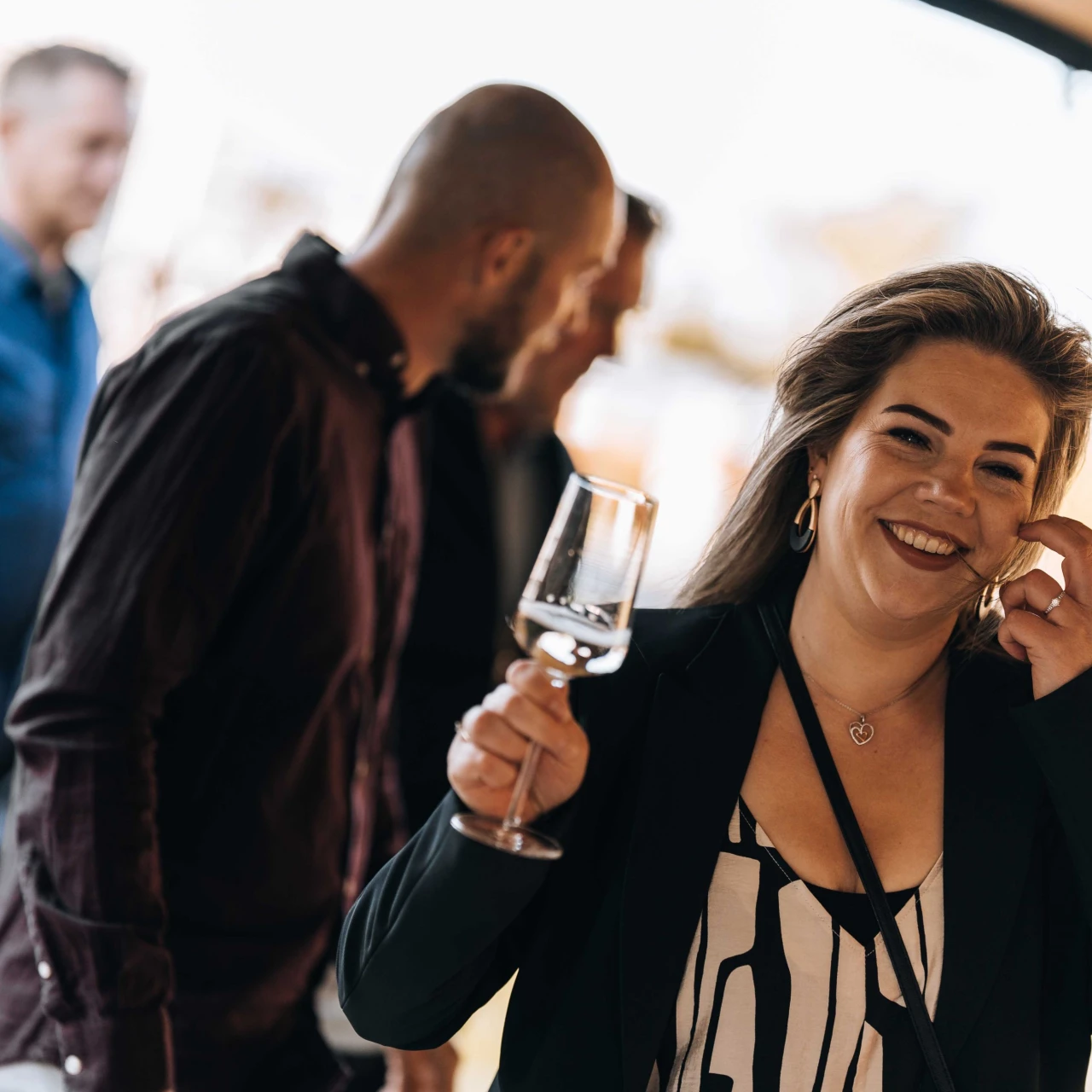 een vrouw die lacht met een glas wijn in haar hand
