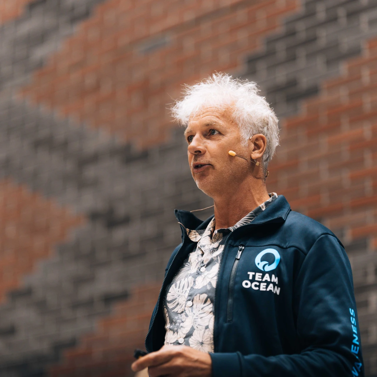 een man met wit haar die met een microfoon staat de praten