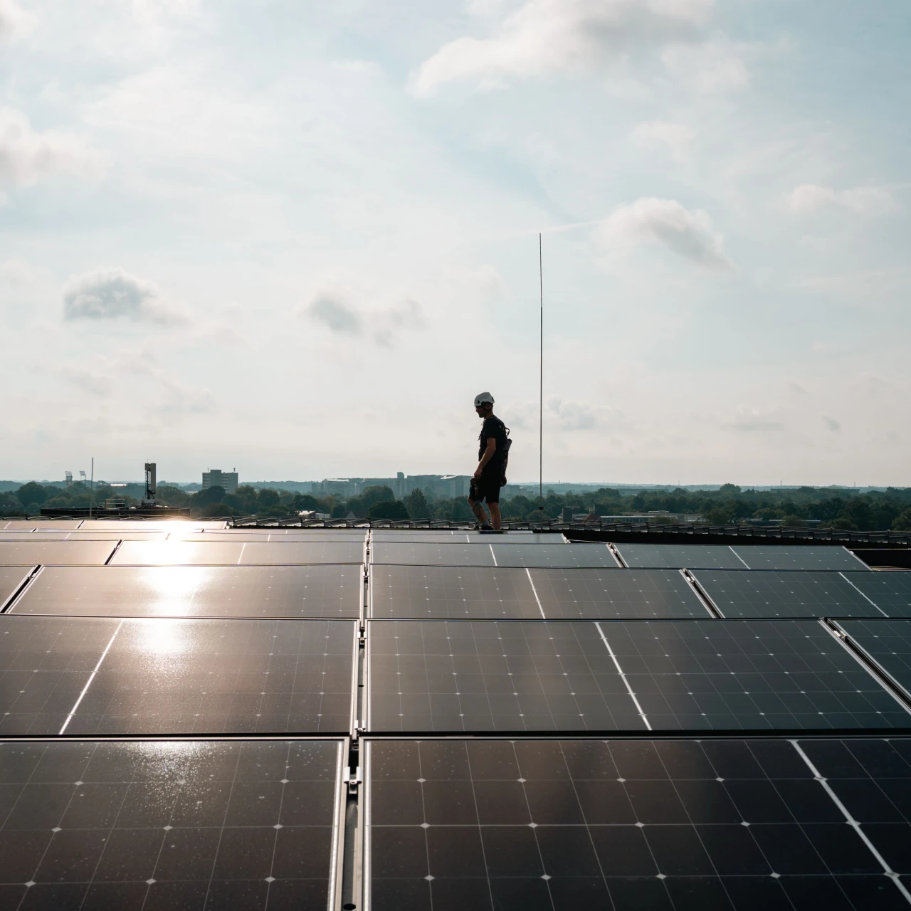 een man die loopt op een dak achter zonnepanelen