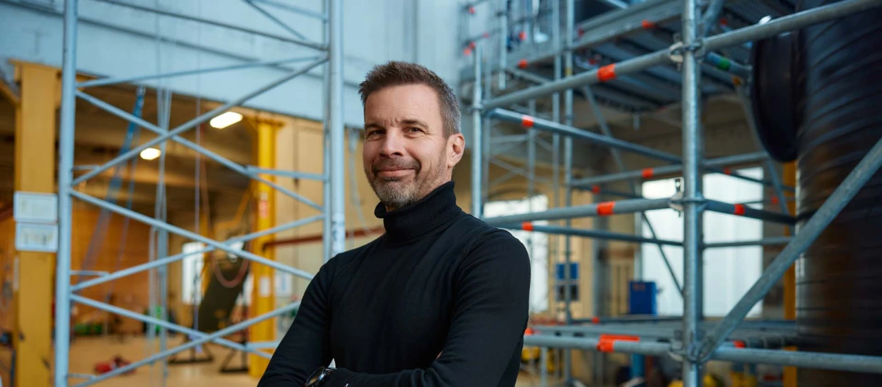 blije man met armen over elkaar poserend in loods