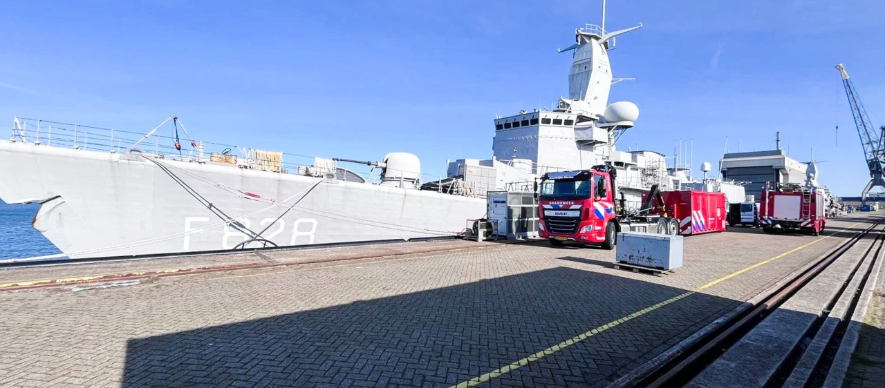 een brandweerwagen in het rood voor een groot schip van de marine