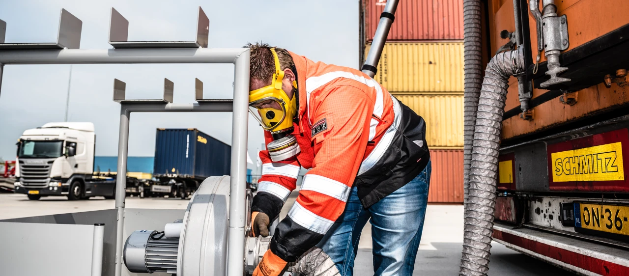 persoon met gasmasker bezig met een slang