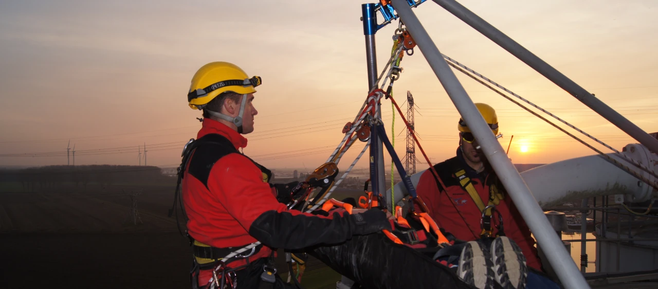 mannen op hoogte met harnas en helm op en man in brancard