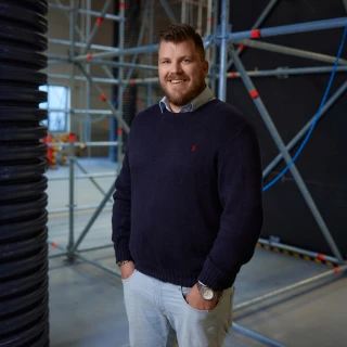 blije man poserend in hal met hand in zak