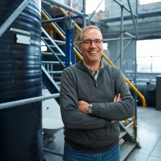 blije man in loods poserend met armen over elkaar