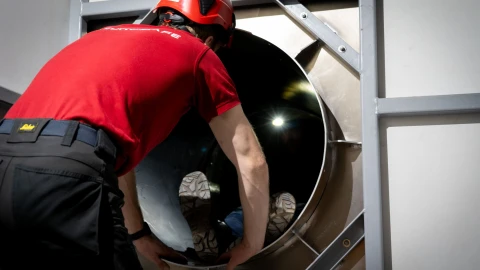 man die persoon helpt in besloten ruimte met helm op