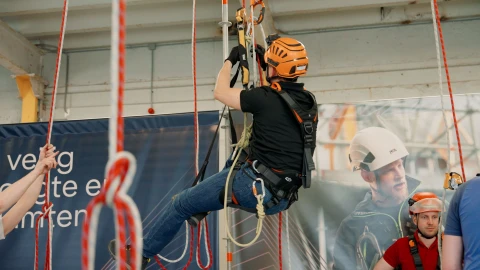 man in harnas aan touwen hangend