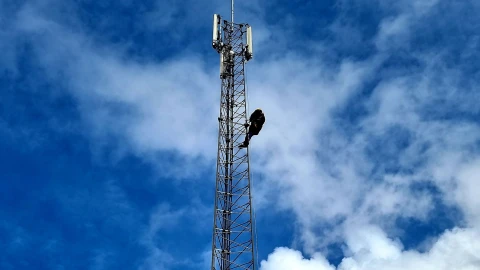 een hoogspanningsmast met een medewerker erin