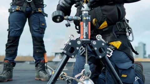 mannen op plat dak met harnas, helm en veiligheidsapparatuur