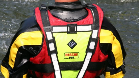 man met reddingsvest en helm bij water