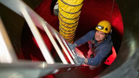 man met helm en lamp op hoofd klimmend op trap in besloten ruimte