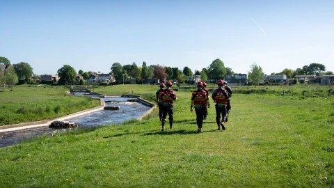 meerdere personen die met een zwemvest langs het water wandelen