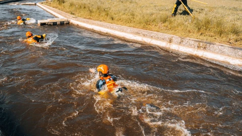 drie personen in snel stromend natuurwater die zichzelf proberen te redden