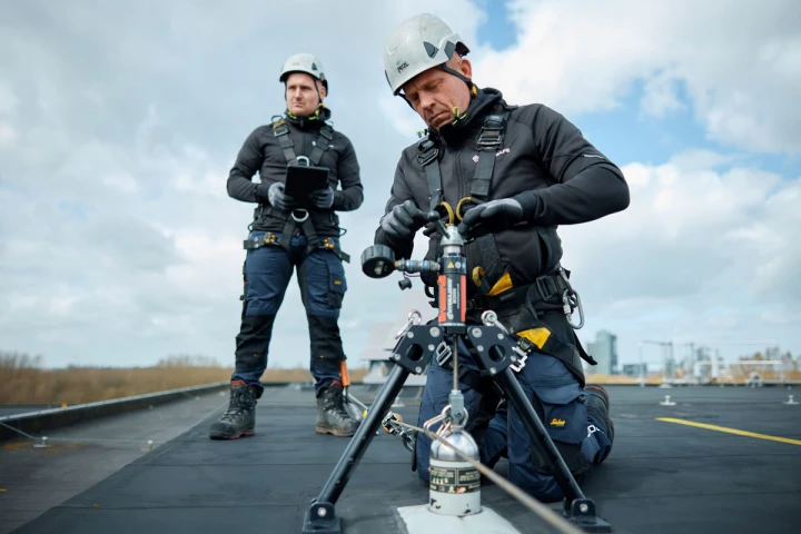 mannen op plat dak met harnas, helm en veiligheidsapparatuur