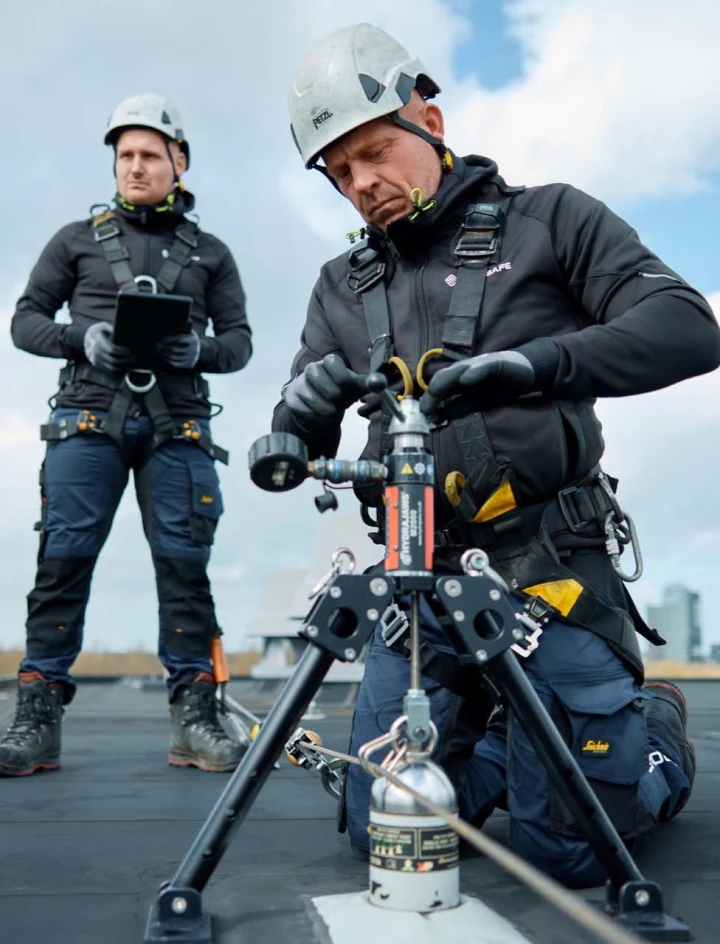 mannen op plat dak met harnas, helm en veiligheidsapparatuur