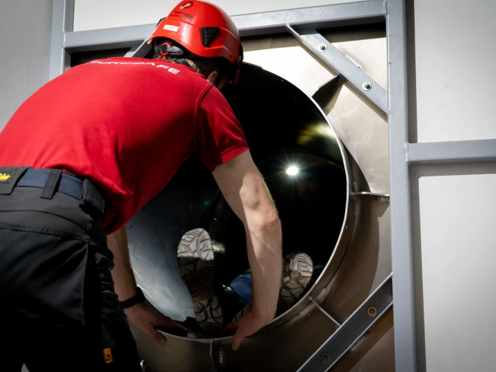 man die persoon helpt in besloten ruimte met helm op