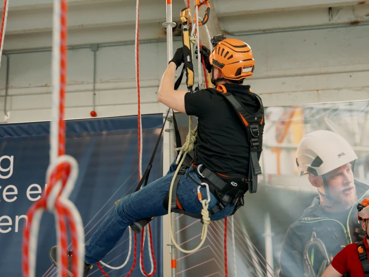 man in harnas aan touwen hangend