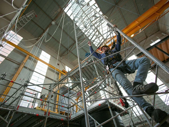 man die ladder beklimd in loods met helm en harnas